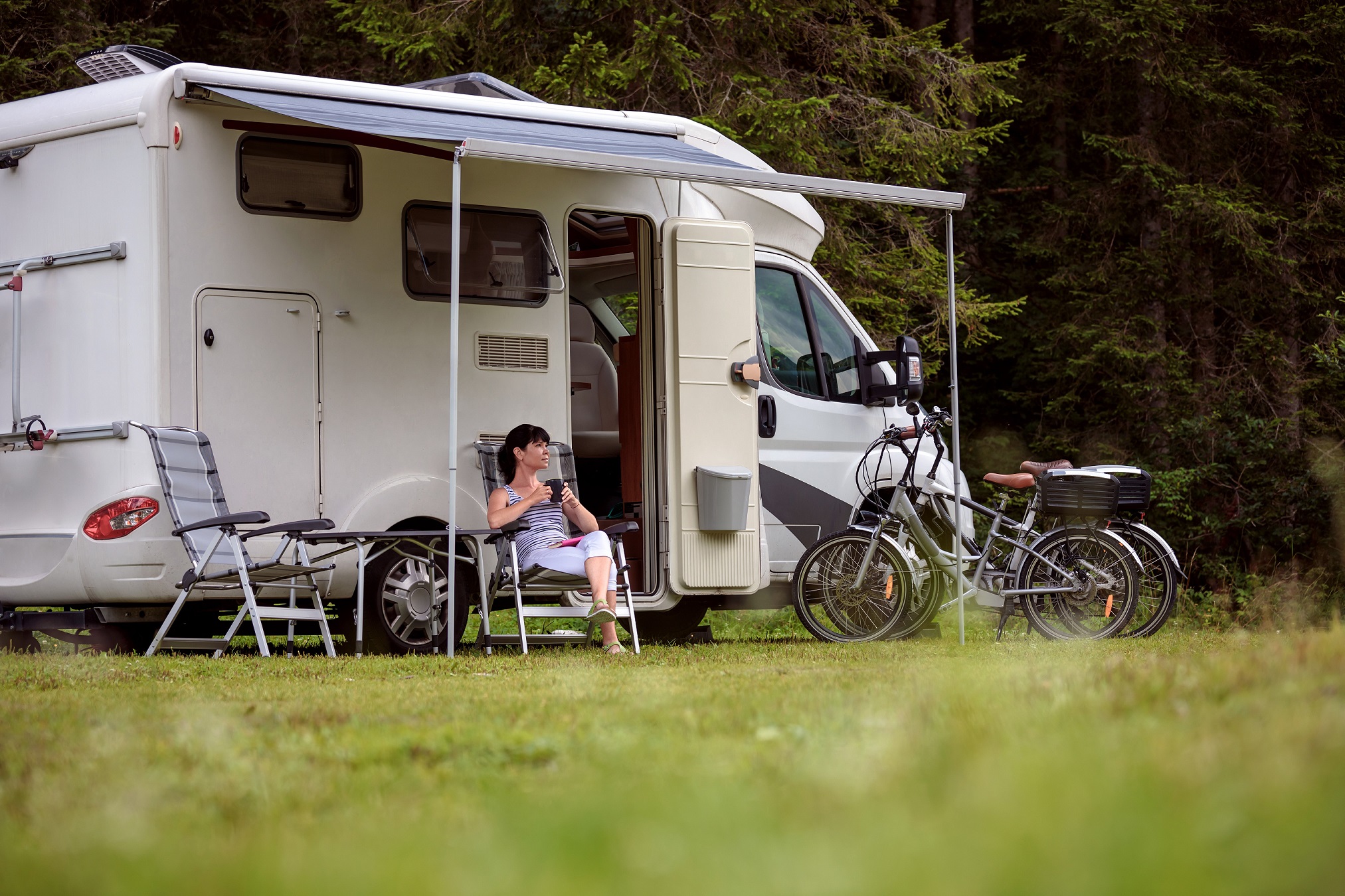 Photo of a camper relaxing with her campervan